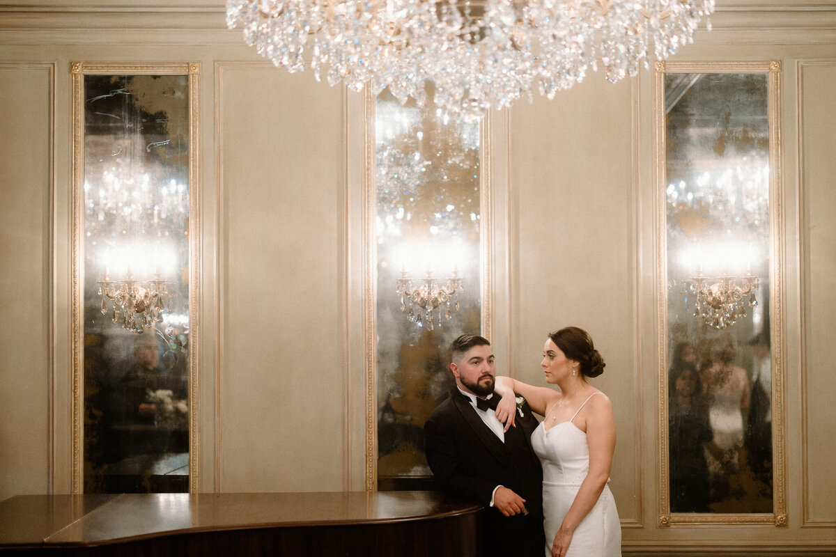 Bride and Groom pose on grand piano in a ballroom