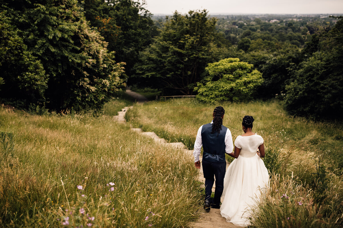 Couple romantically strolling through field on path wedding portrait
