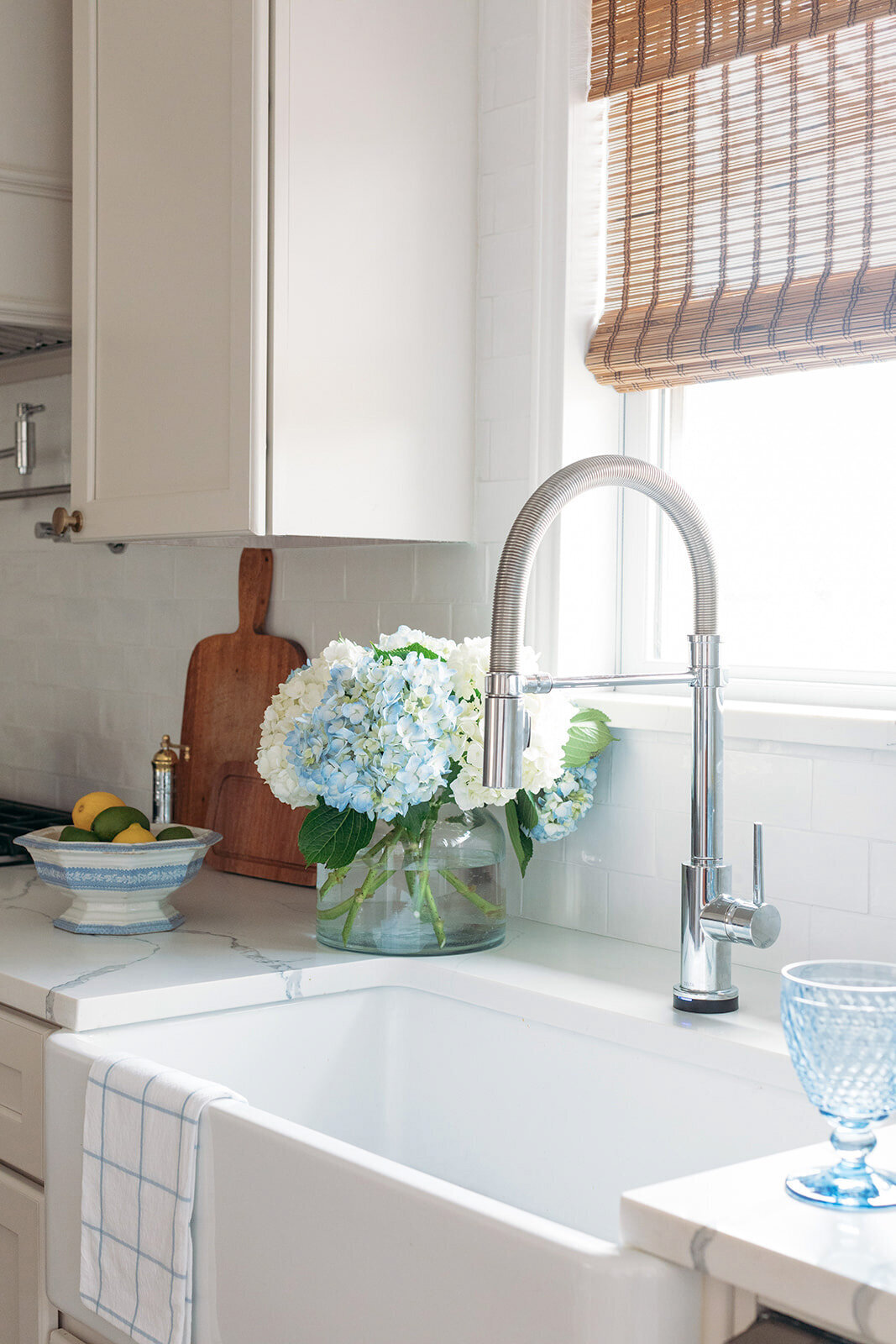 Fresh kitchen design with white porcelain sink and window with bamboo shades