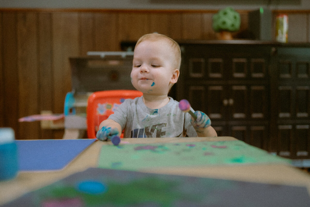 family documentary photo of a child happily playing with an art project