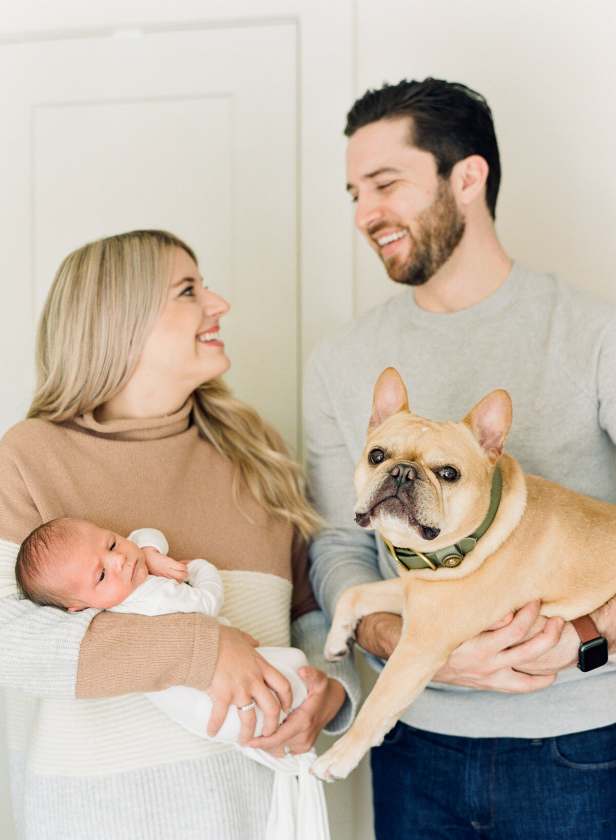 Mom holds newborn while Dad holds their dog for a family portrait during a Raleigh NC newborn session. Photo by Raleigh Newborn Photography A.J. Dunlap Photography.