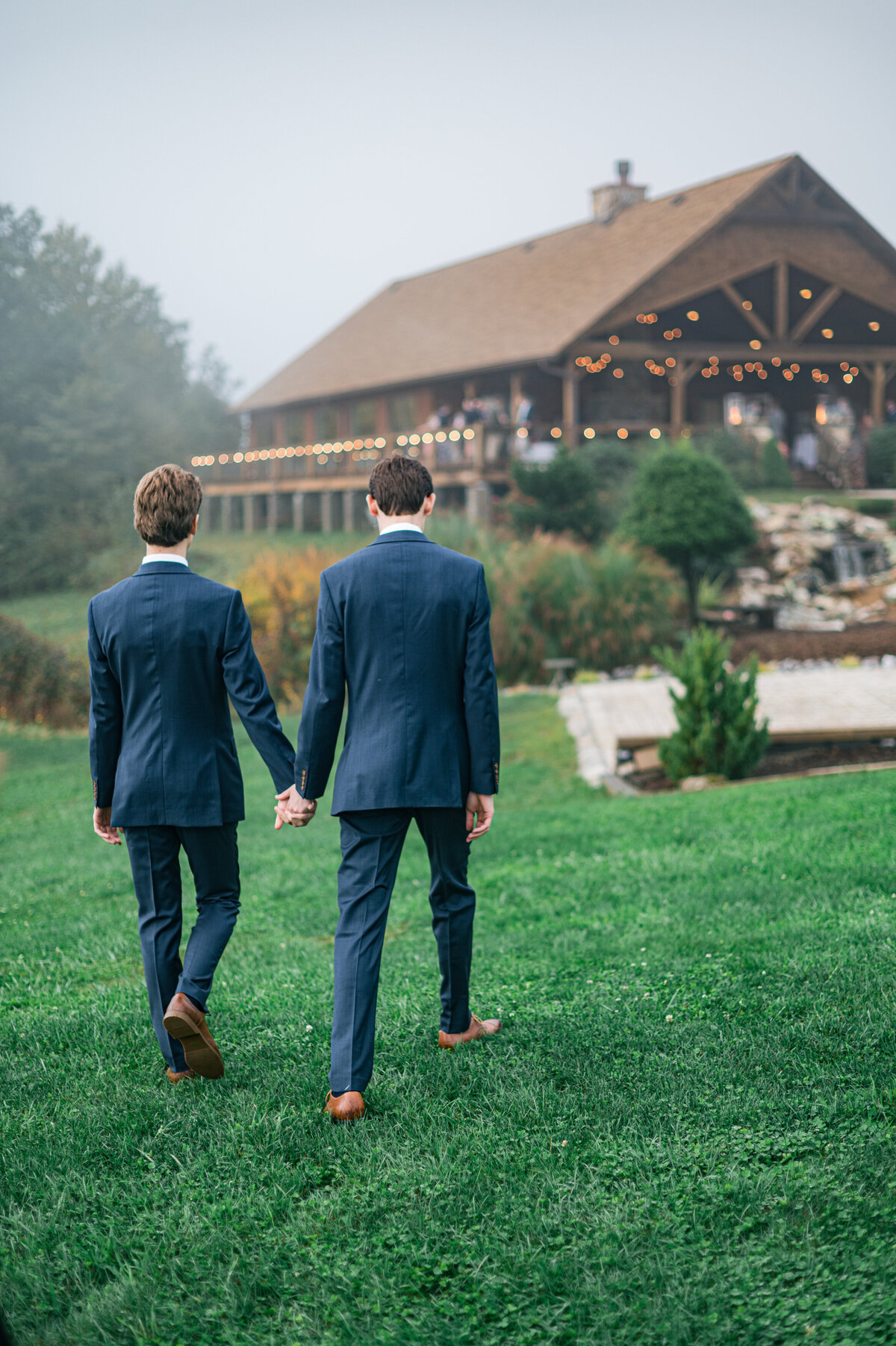 Two grooms walk together to their reception on their wedding day in Boone, NC