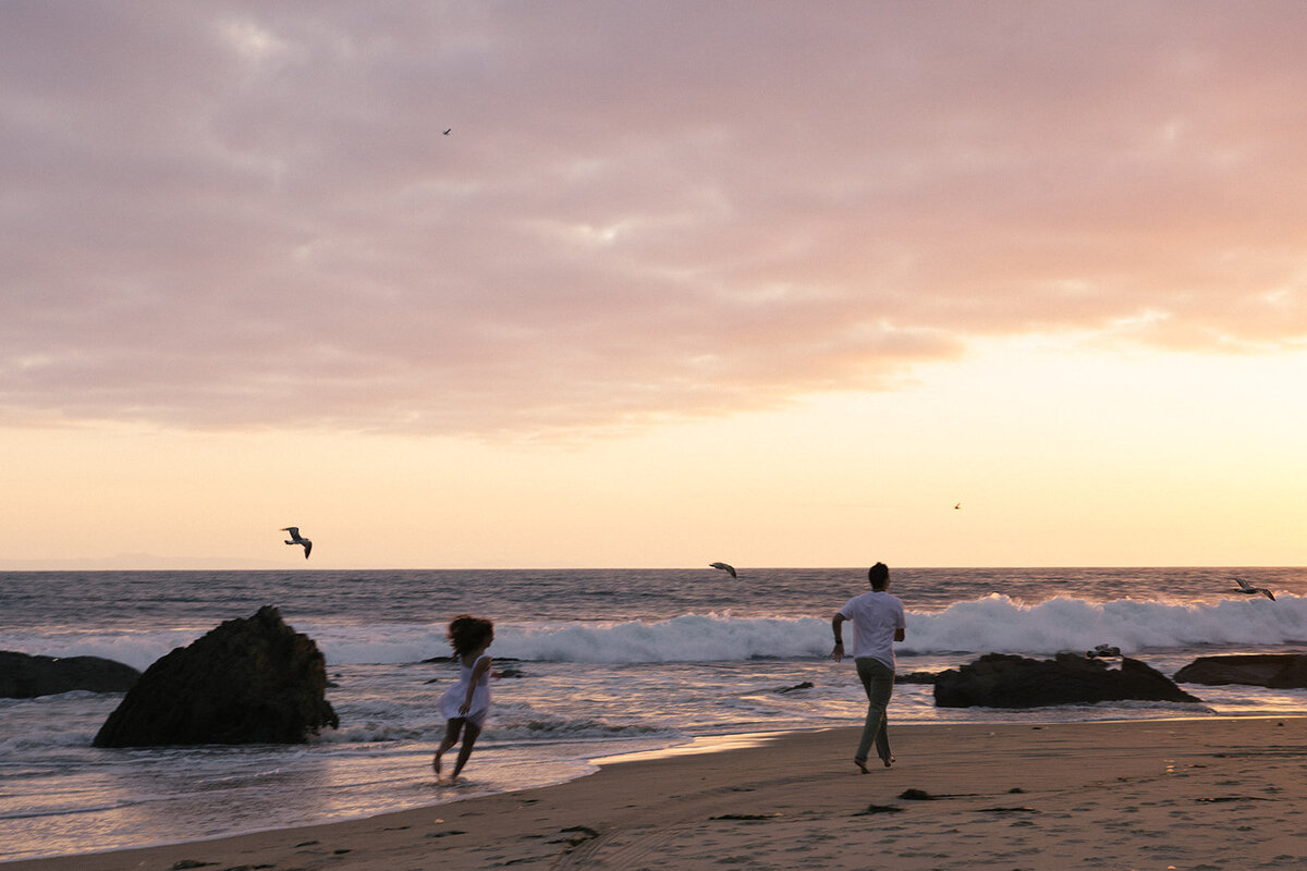 a couple running on the beach in California during their documentary engagement session