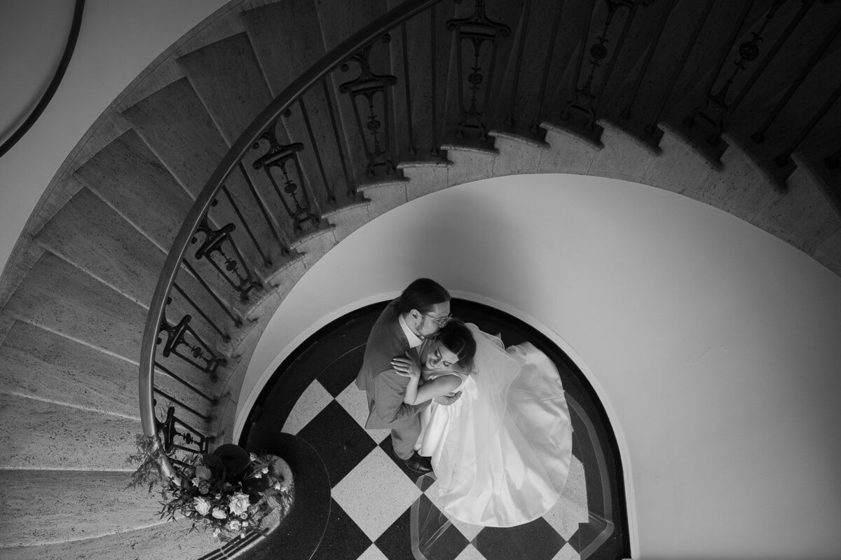 birds eye shot of bride and groom at the bottom of a spiral staircase