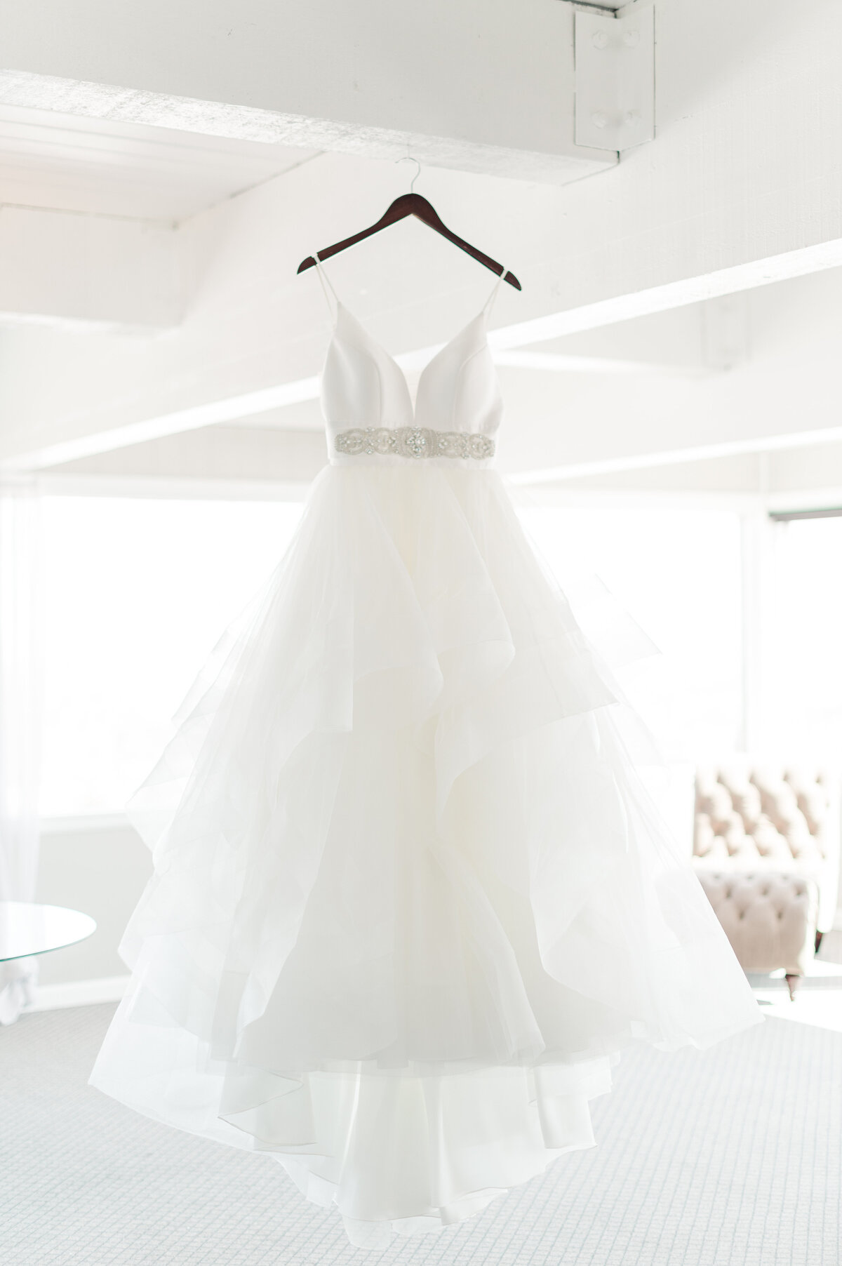 brides dress hanging from the ceiling in a beautifully lit room