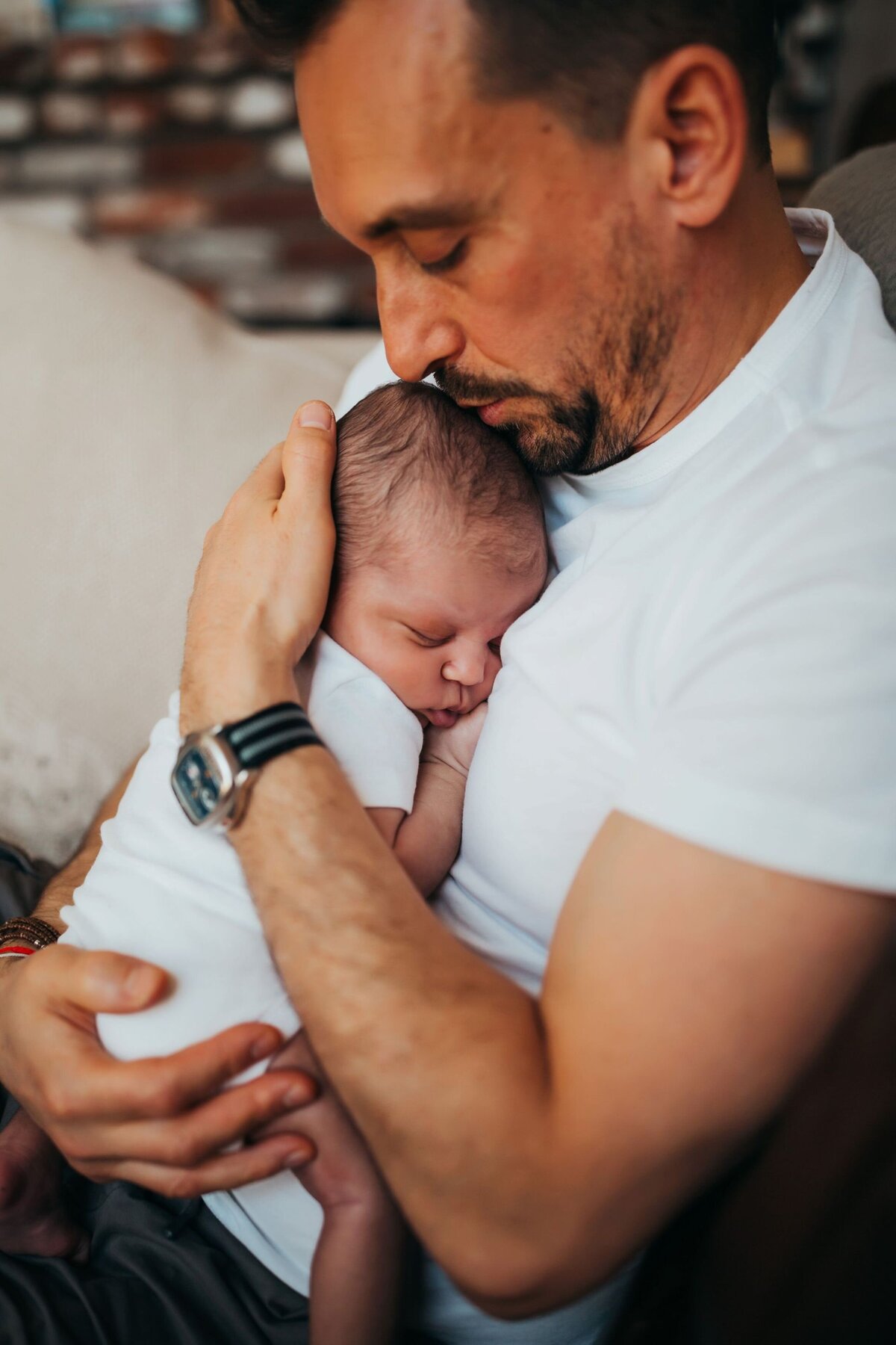 newborn first time dad holding newborn daughter on couch by Huntignton Beach photographer Francesca Marchese Photography