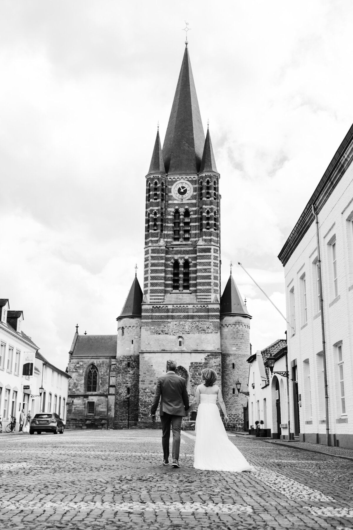 Bruidspaar loopt over plein in thorn witte stadje limburg richting kerk zwartwit foto