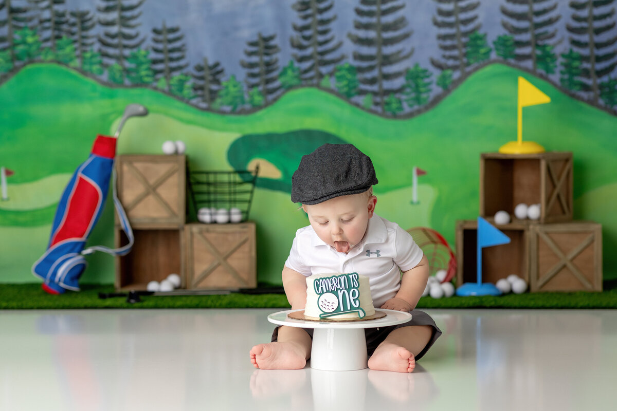 One year old Tampa baby enjoying a personalized luxury cake smash session with golf themed decorations