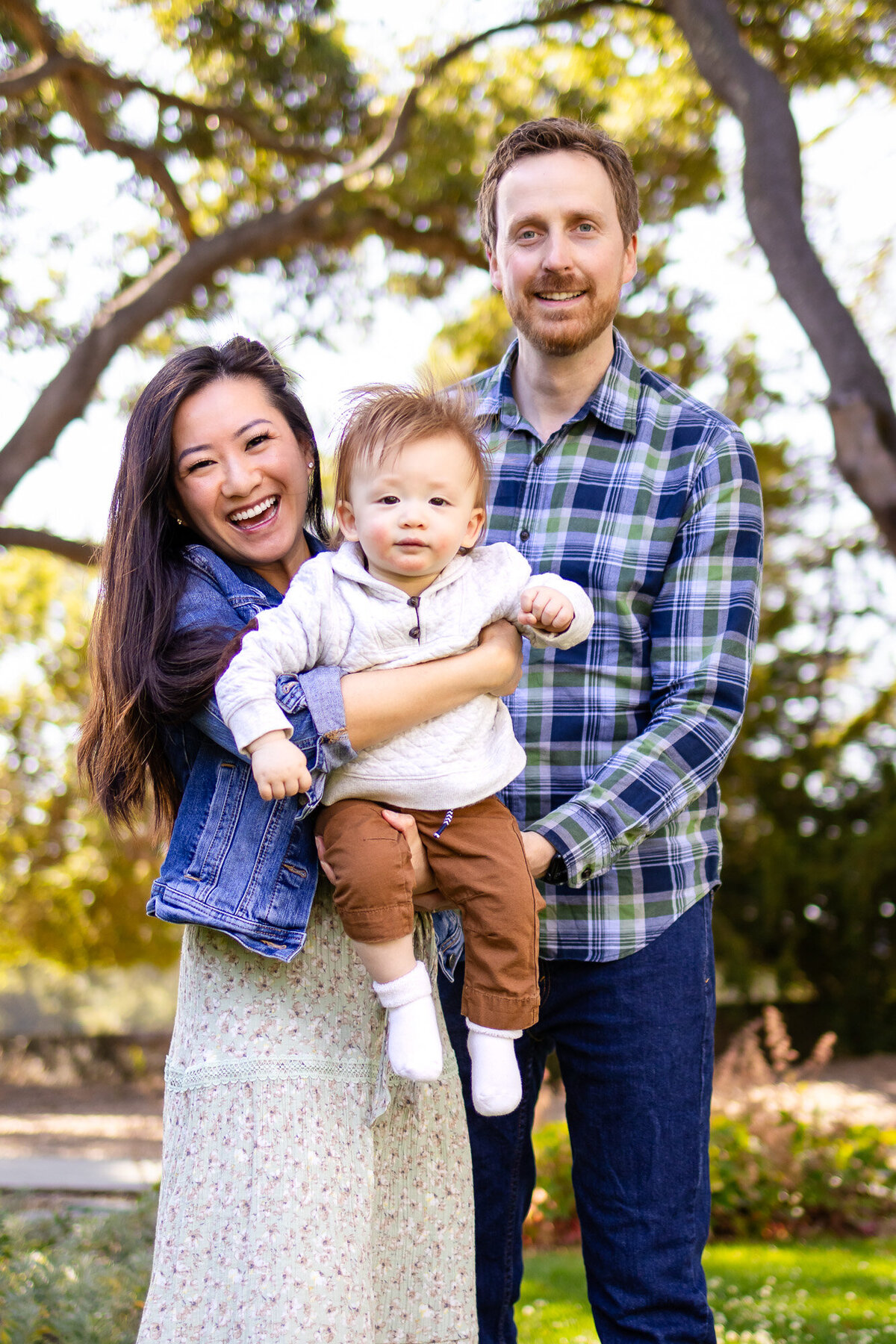 San Francisco Peninsula family photographer  Joyful parents holding baby boy close during a candid outdoor family session 