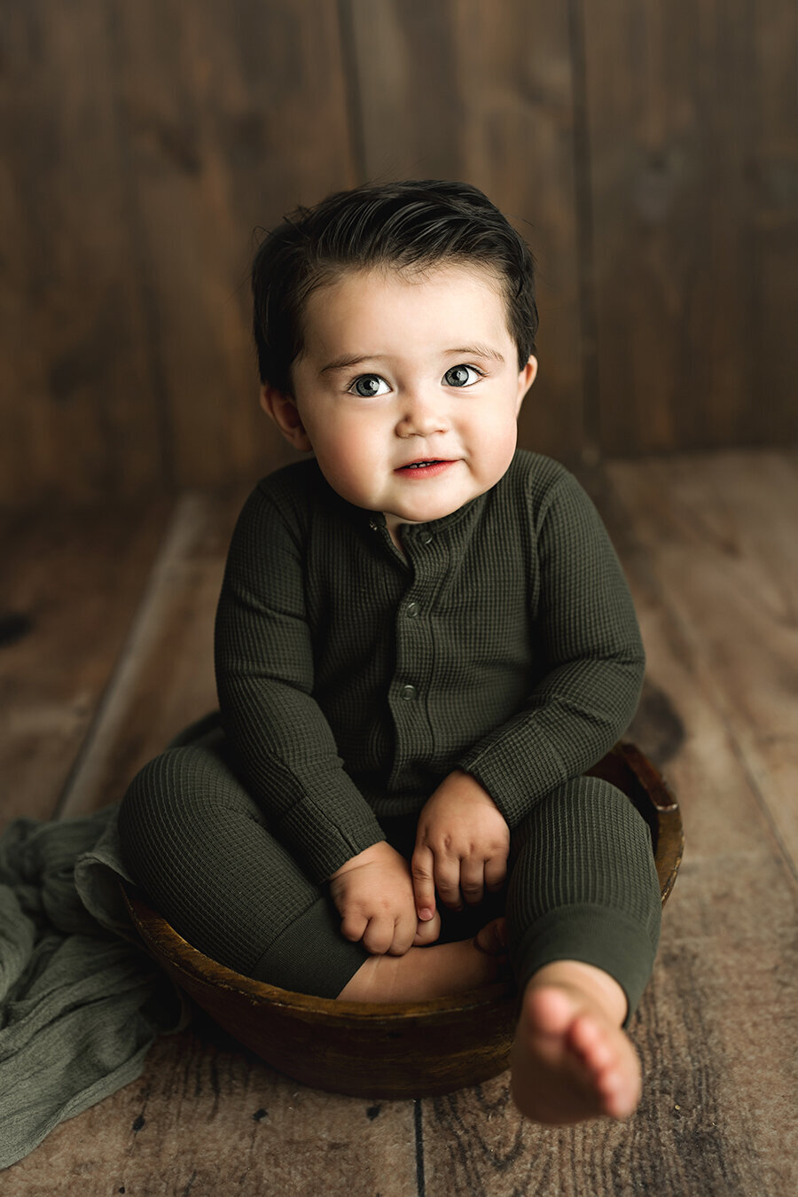Adorable baby boy sitting in a bowl in a photography studio in Fort Collins