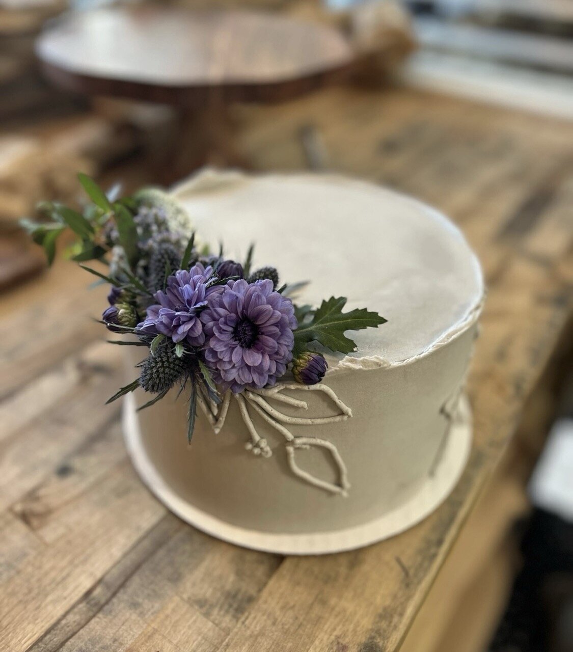 Gluten-free white buttercream cake adorned with purple flowers, created by Grain Artisan Bakery for weddings and special occasions in Snohomish, WA.