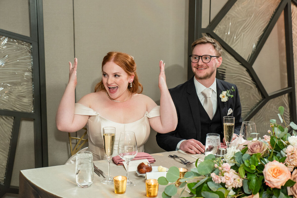 A bride and groom are sitting at a table with champagne glasses
