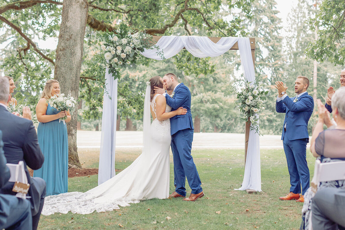 Couple sharing first kiss at wedding ceremony at Royal Oaks Country Club in Vancouver Washington