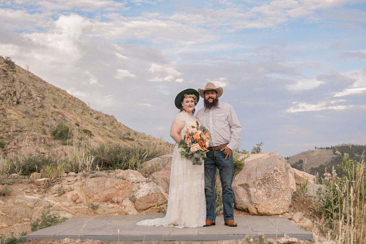 The just married couple smile for a portrait at a mountain overlook in the foothills near Boulder, Colorado
