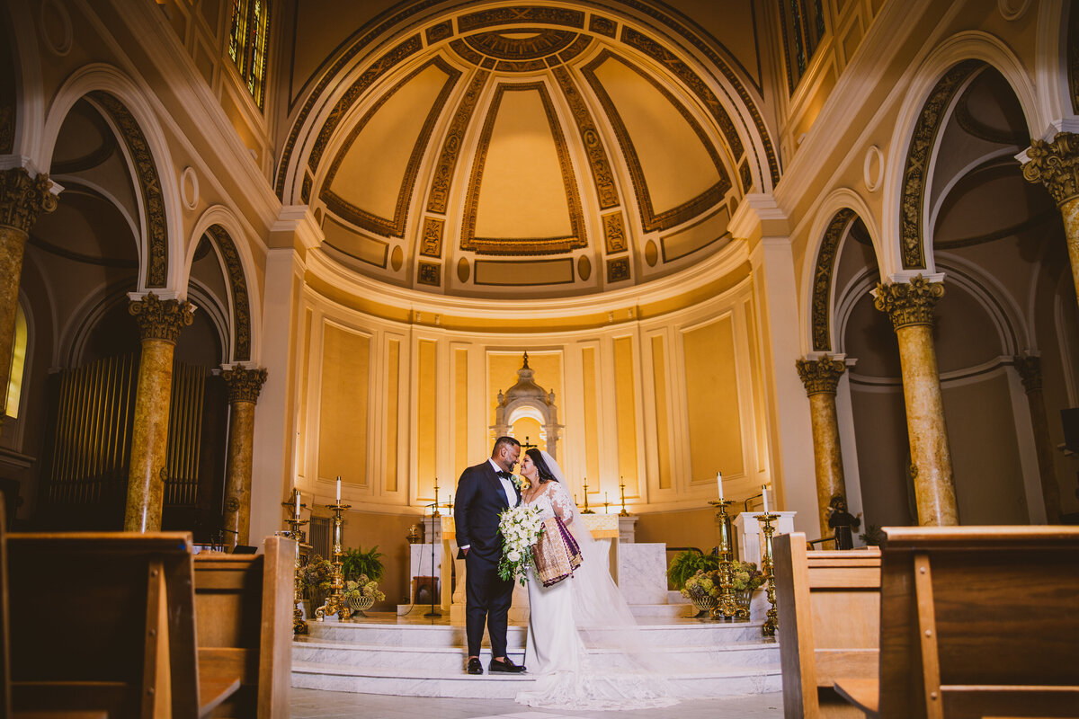 indian christian bride and groom share moment inside the church altar at the immaculate conception roman catholic church in nj