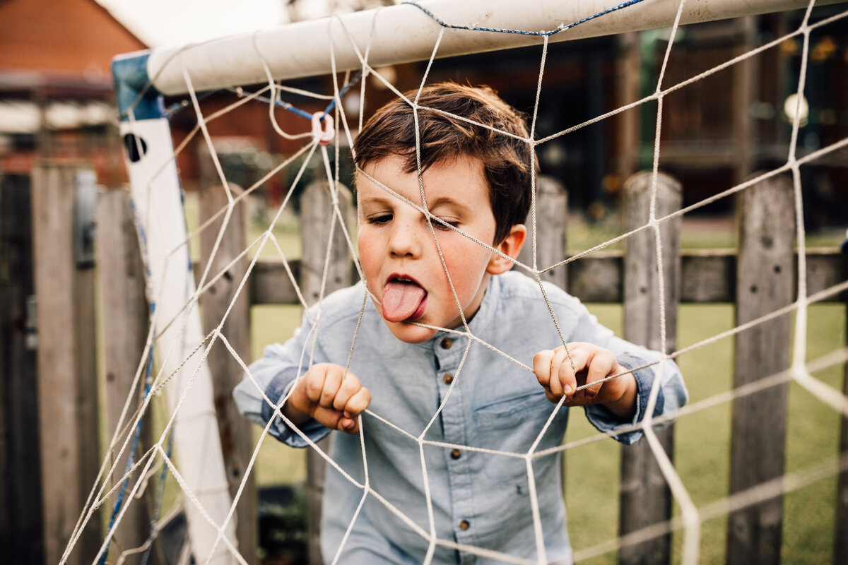 Young boy playing outside in football net