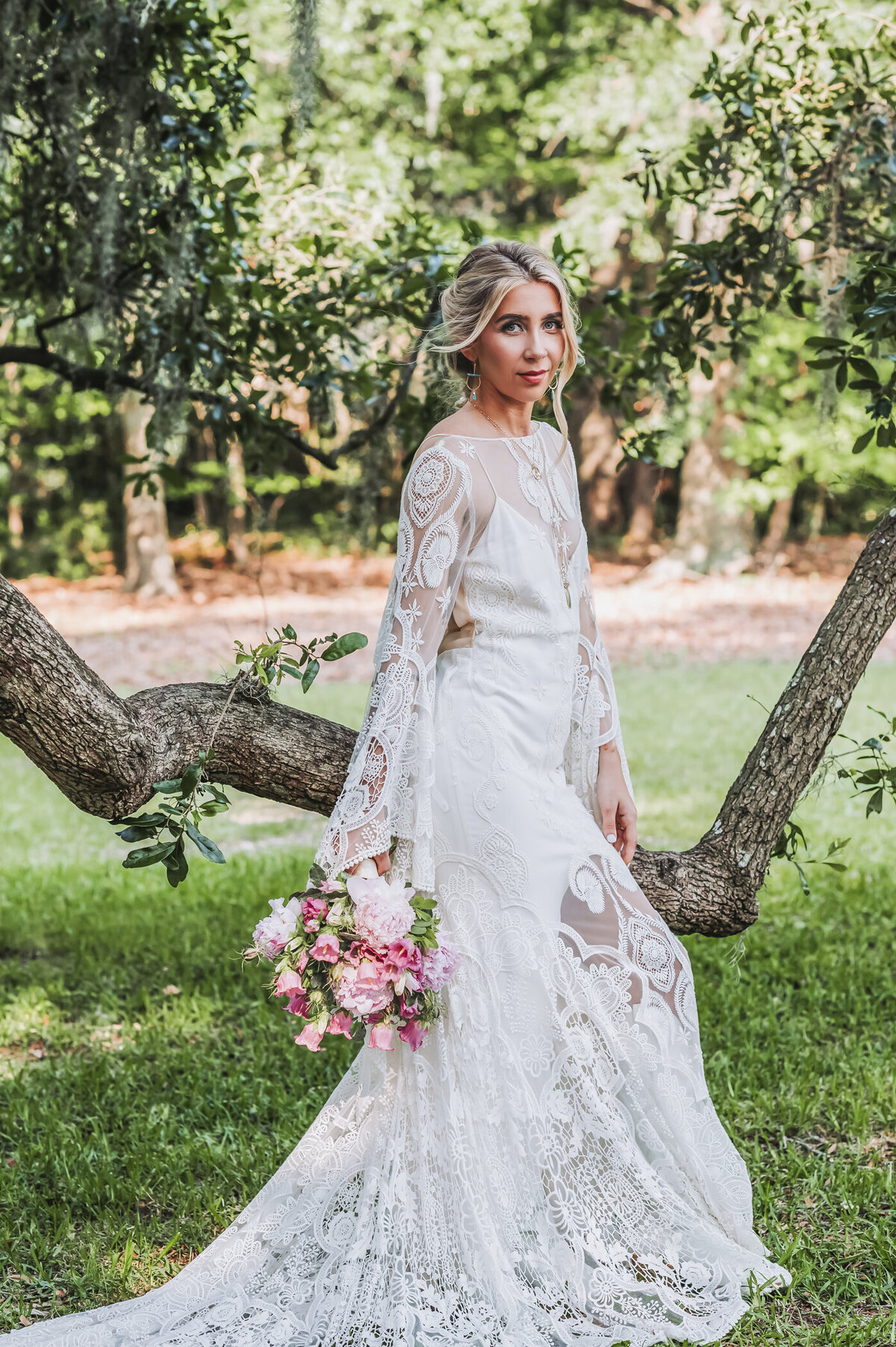 Boho bride posing next to a tree under spanish moss