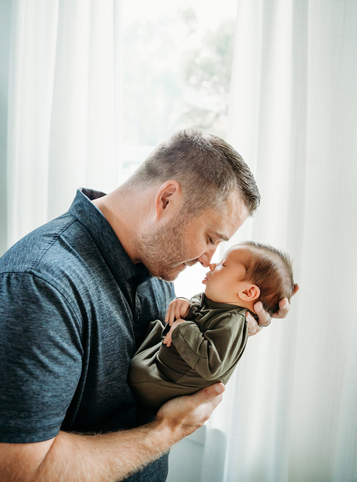Newborn Photographer, dad tenderly brings his newborn son nose-to-nose