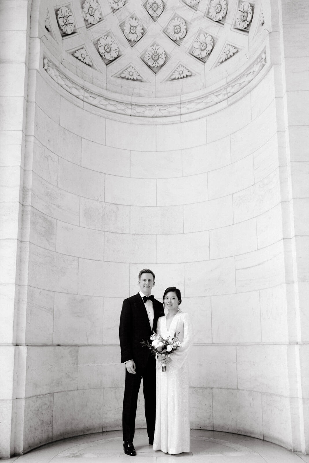 The bride and the groom are inside New York Public Library, NYC, with a very high and beautiful ceiling. Image by Jenny Fu Studio