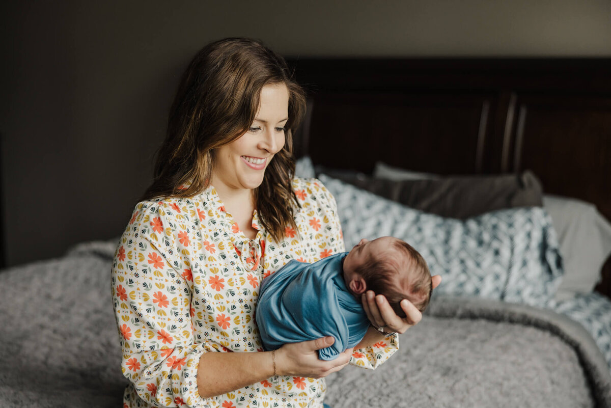 lifestyle newborn portrait of mother holding newborn baby boy while sitting on bed in Longview, TX home