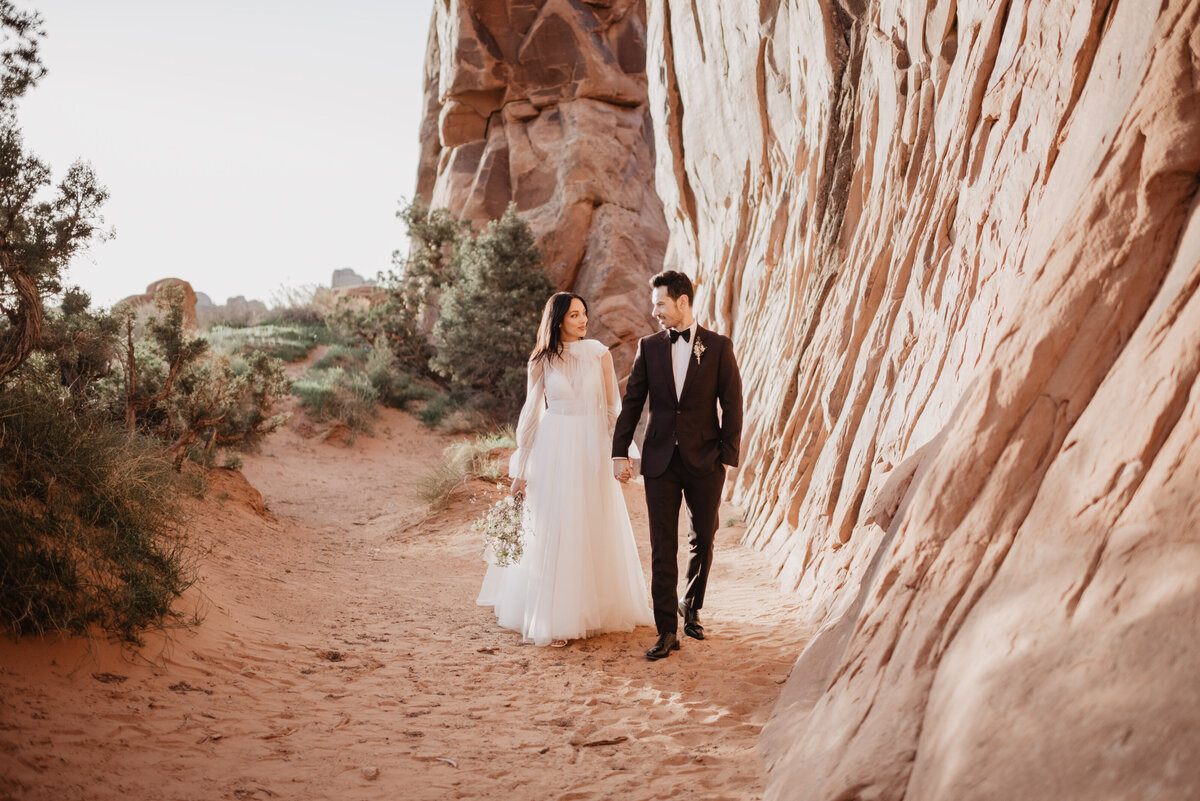 Utah elopement photographer captures couple walking hand in hand during bridal portraits
