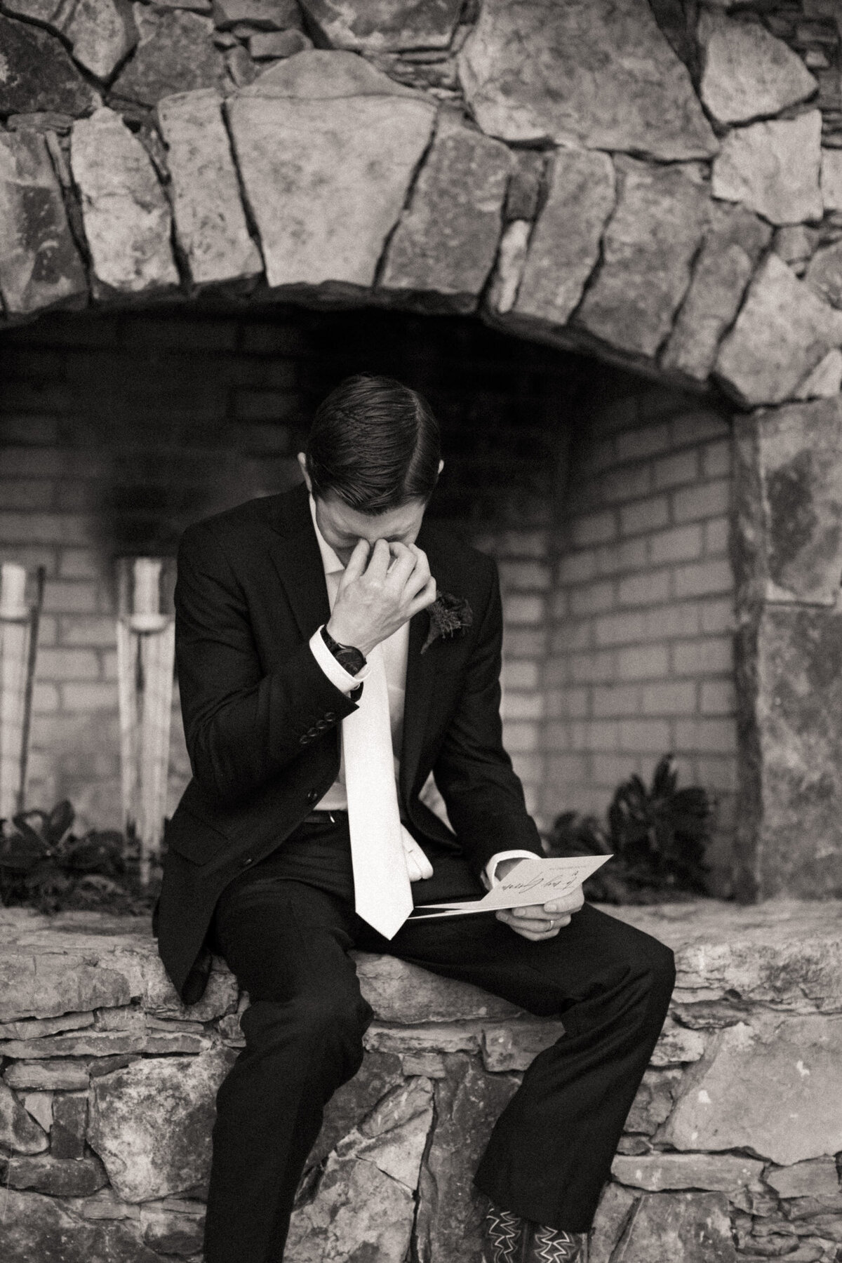 Emotional groom wiping away tears as he reads the letter from his bride