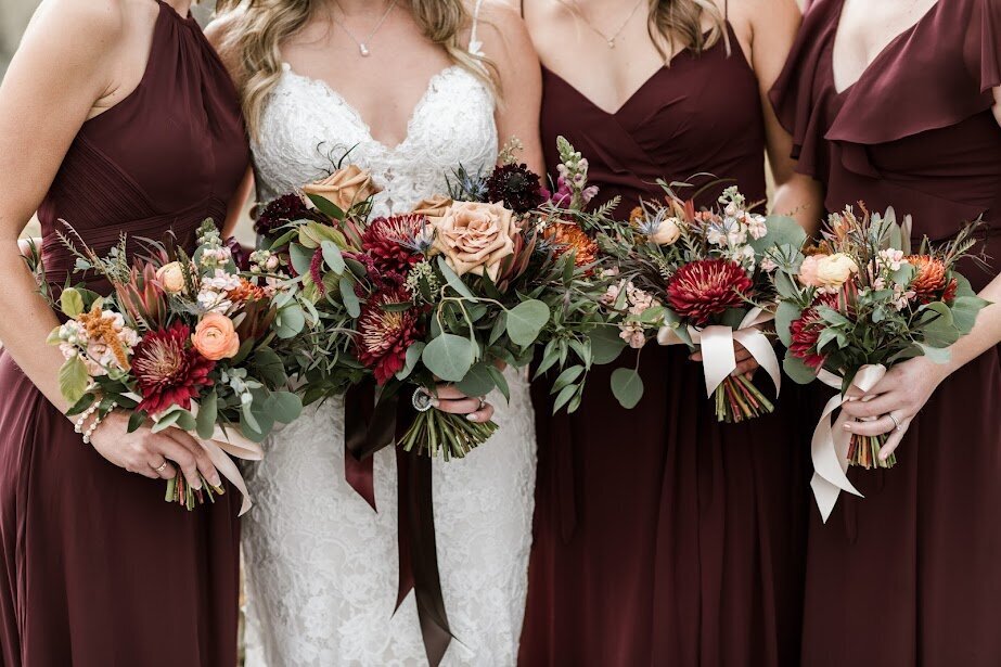Warm and moody bridal party bouquets with burgundy mums and toffee roses