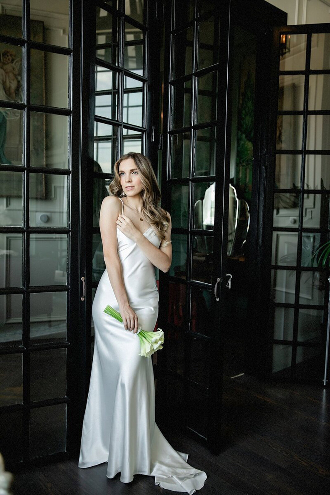 Bride Anna in a silk wedding gown holding a modern white calla lily bouquet at The Mason wedding venue in Dallas.