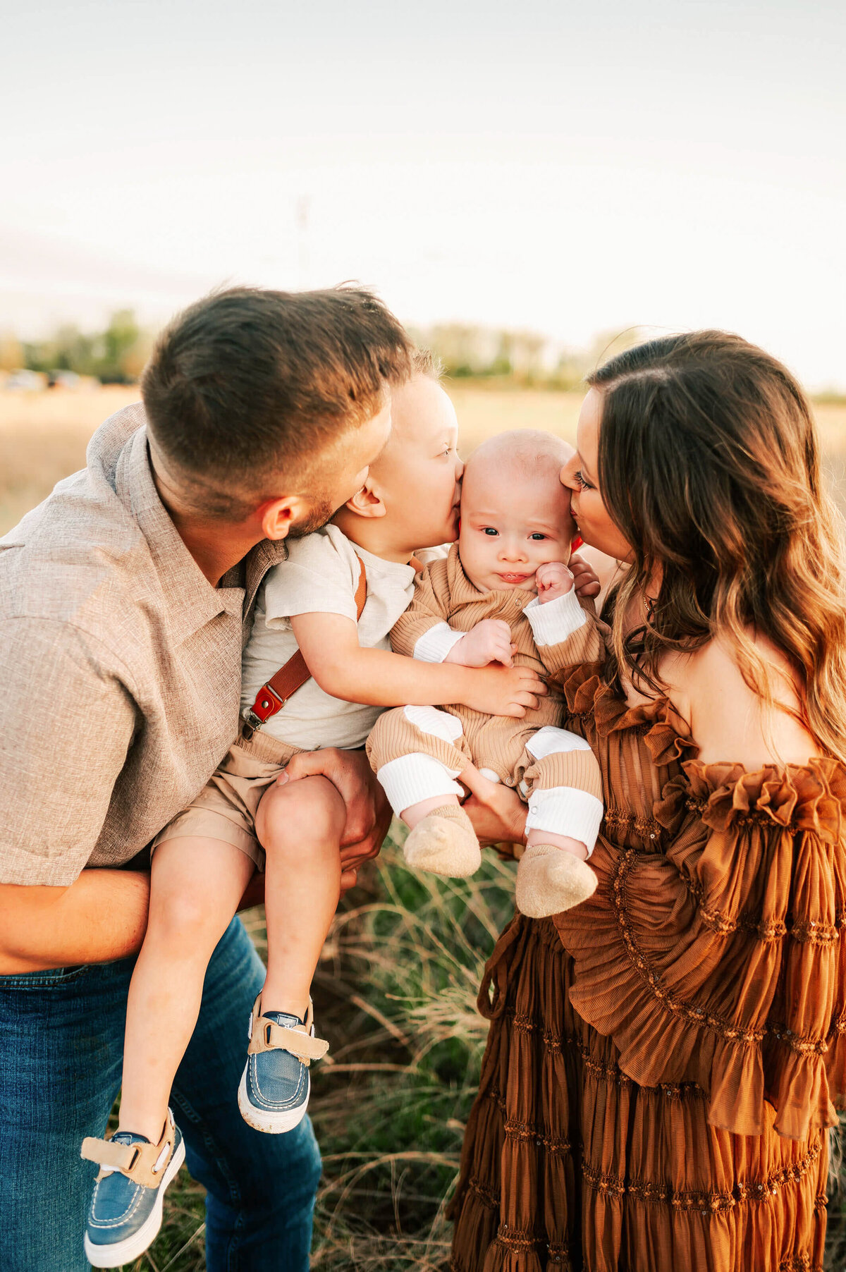family pictures in Branson of family kissing baby outdoors at sunset