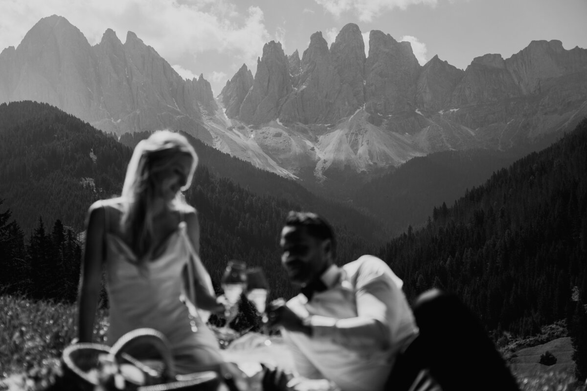 Black and white photo of couple toasting during elopement picnic