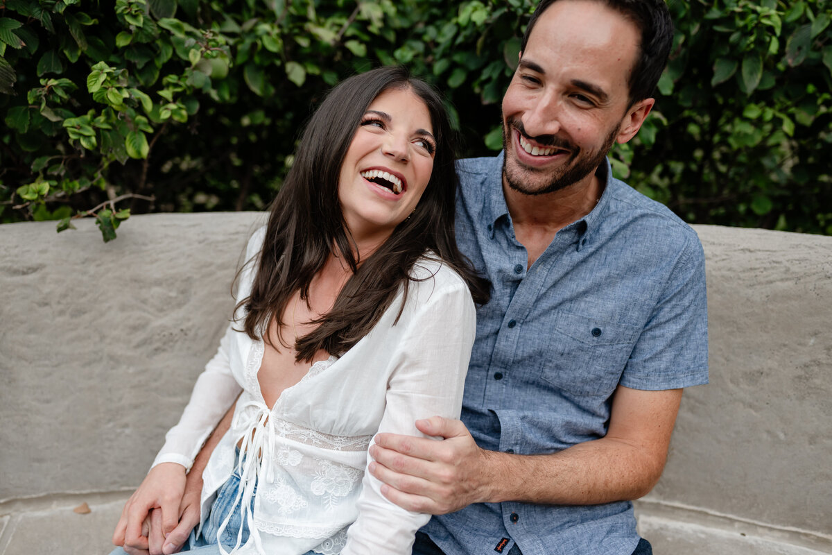 A couple laughs together on a bench