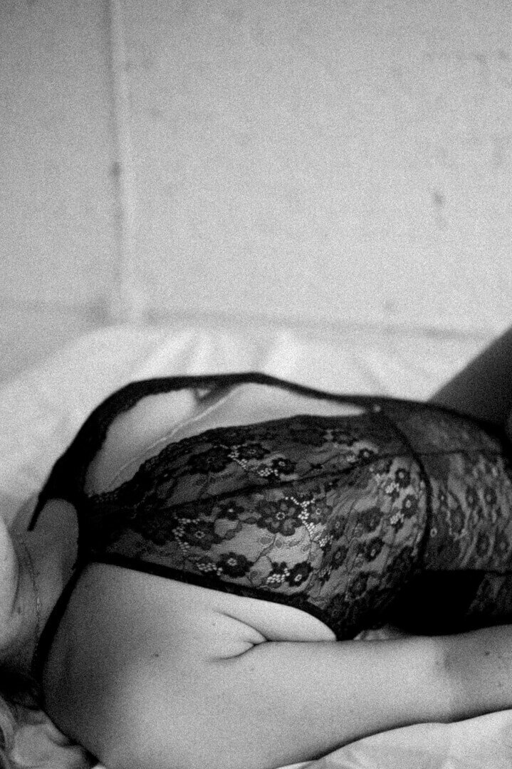 womans chest laying down  wearing black lace lingerie and body chain
