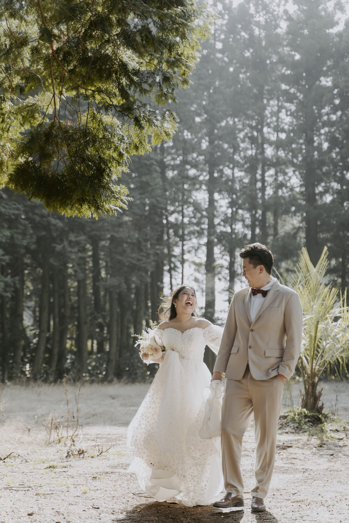 the couple holding hands and laughing at the forest in jeju island