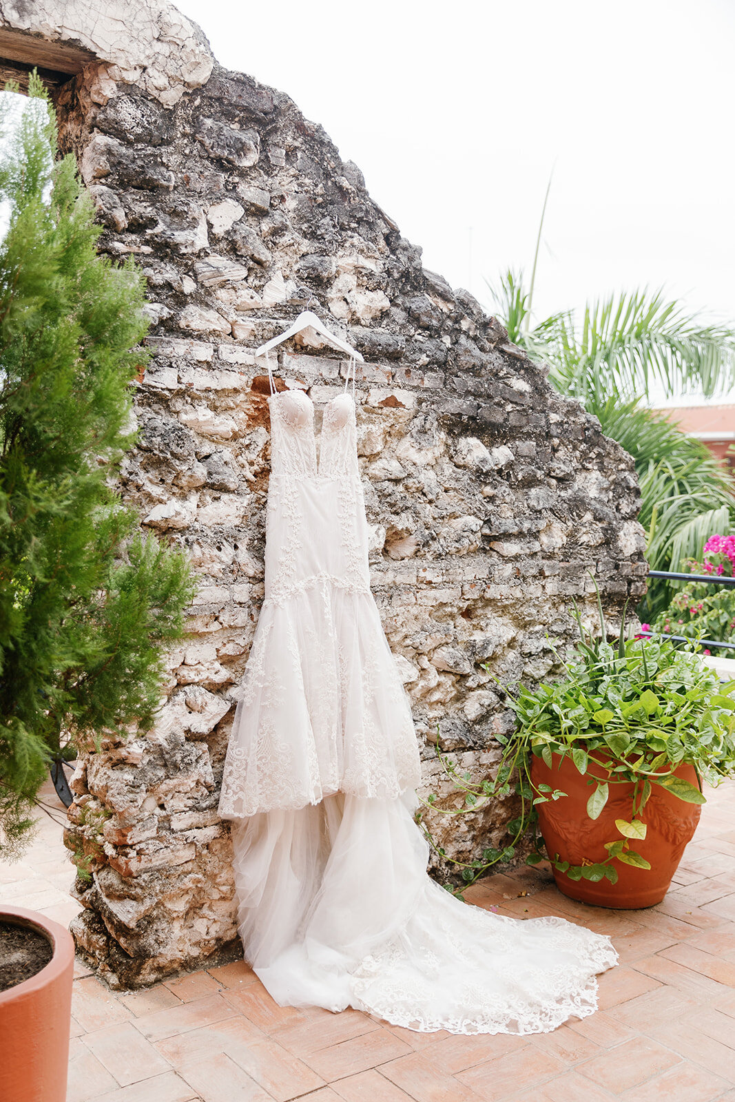 Victoria’s lace wedding gown elegantly displayed against an old stone wall at her Cartagena Colombia wedding venue.