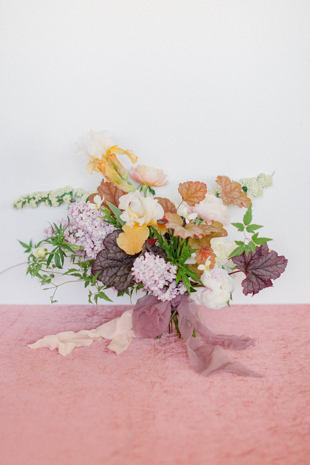 A springtime bouquet of lilacs and textured leaves tied by ribbon, at a Montreal studio. 
