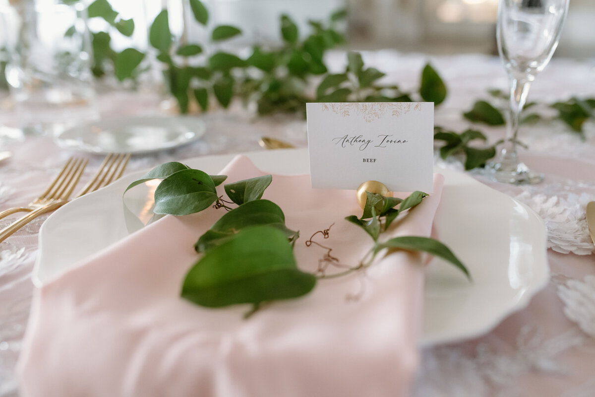 Luxury wedding place card with guest name on soft pink napkin, part of elegant wedding day stationery.