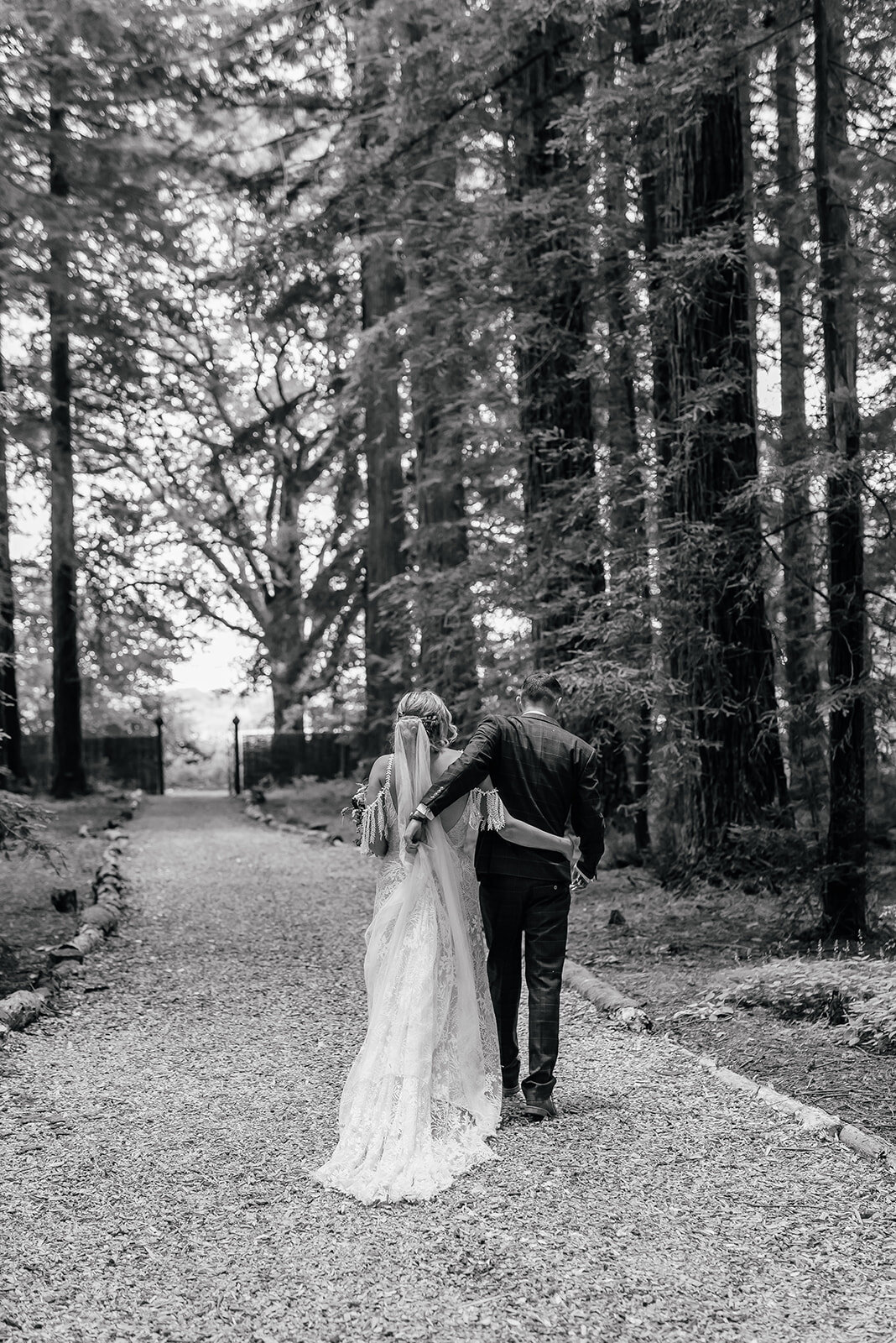 Bride and Groom walking down woodland pathway with their arms around eachother