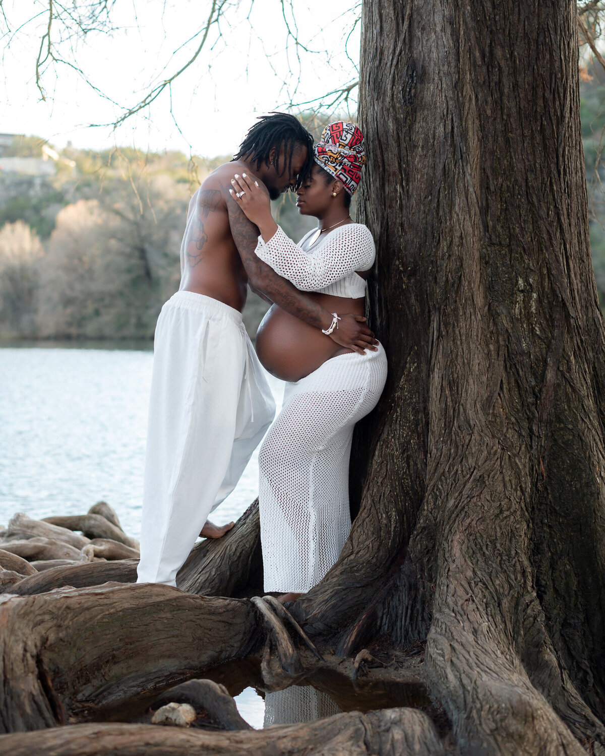 Expecting couple embracing by lake during outdoor maternity photography session in Austin Texas