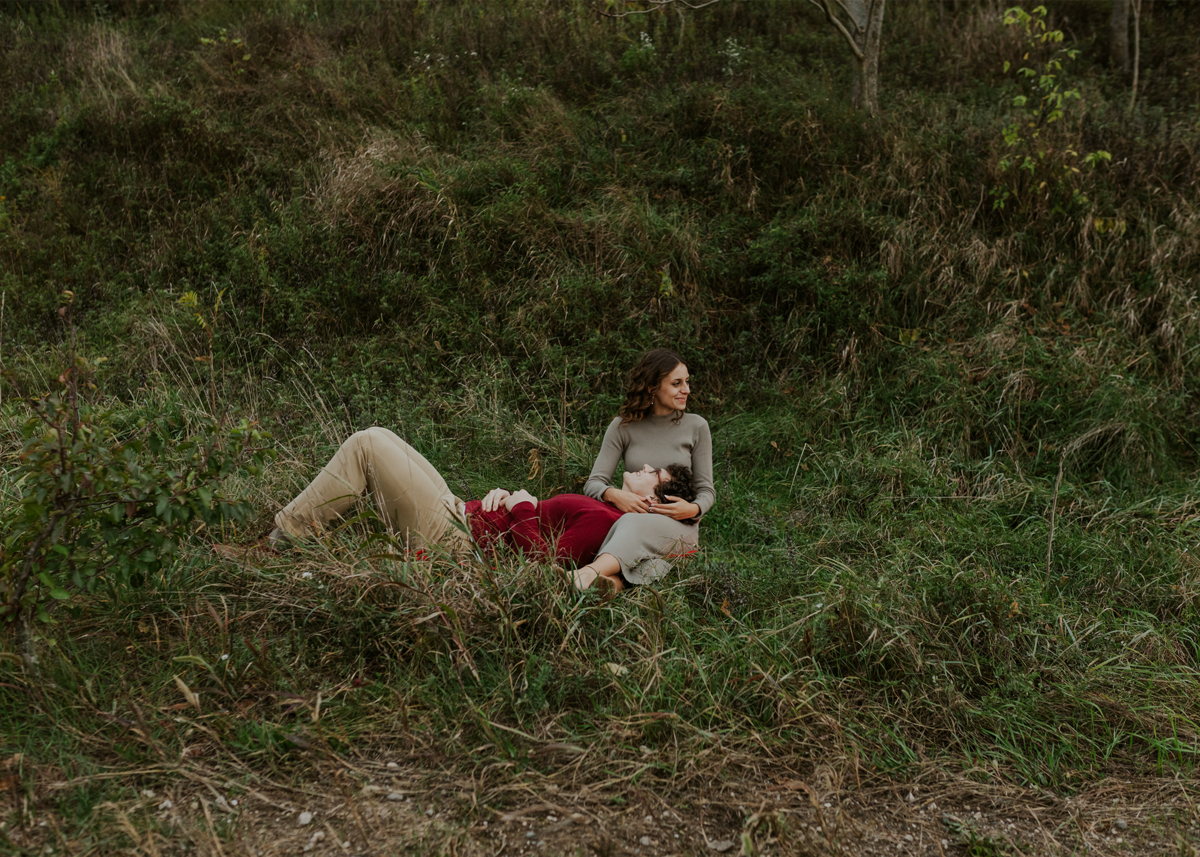 Bride laying in a grassy field with floral bouquet, whimsical wedding portrait.