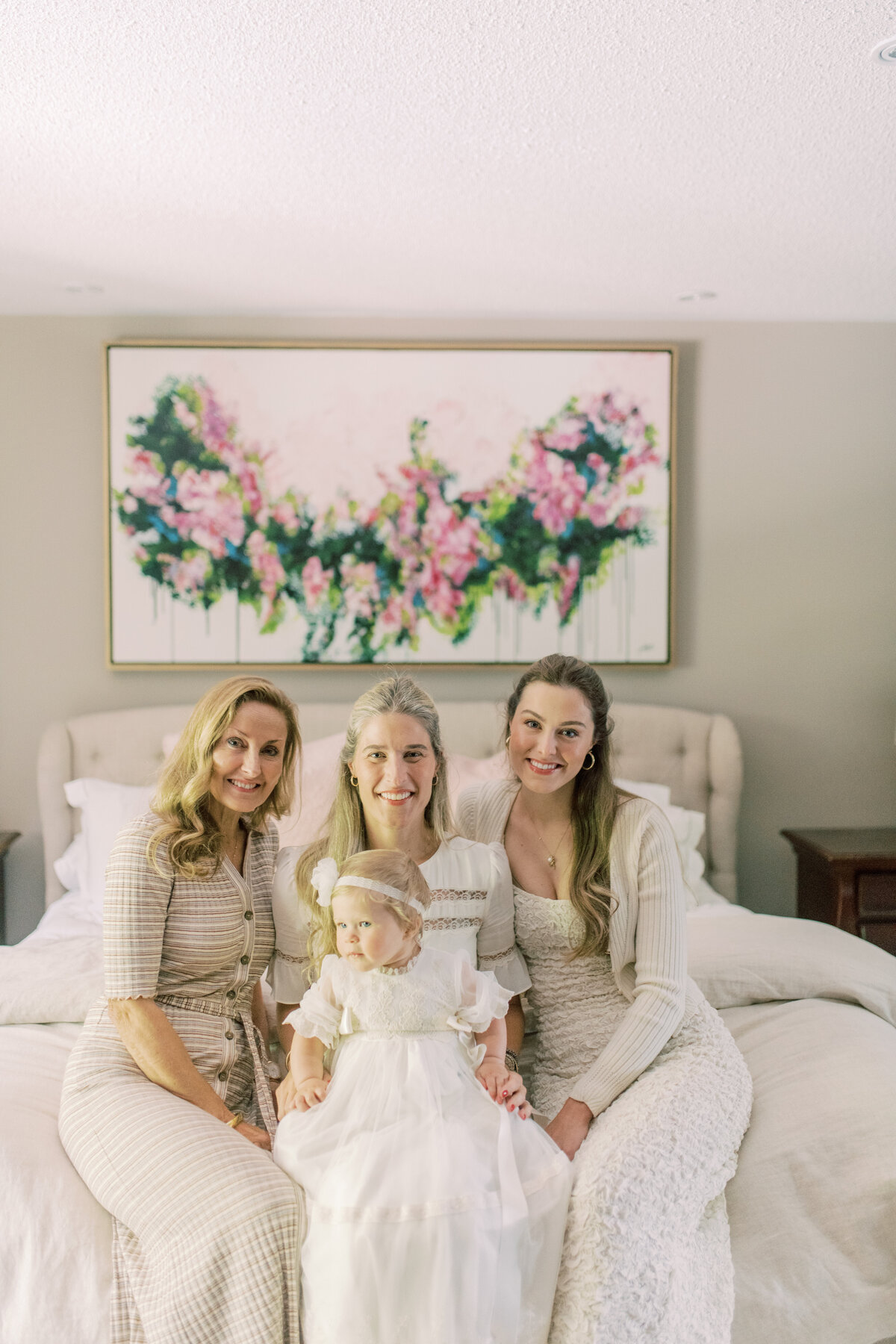 Grandmother, mother, and godmother gather around baby girl—three generations of grace and heritage