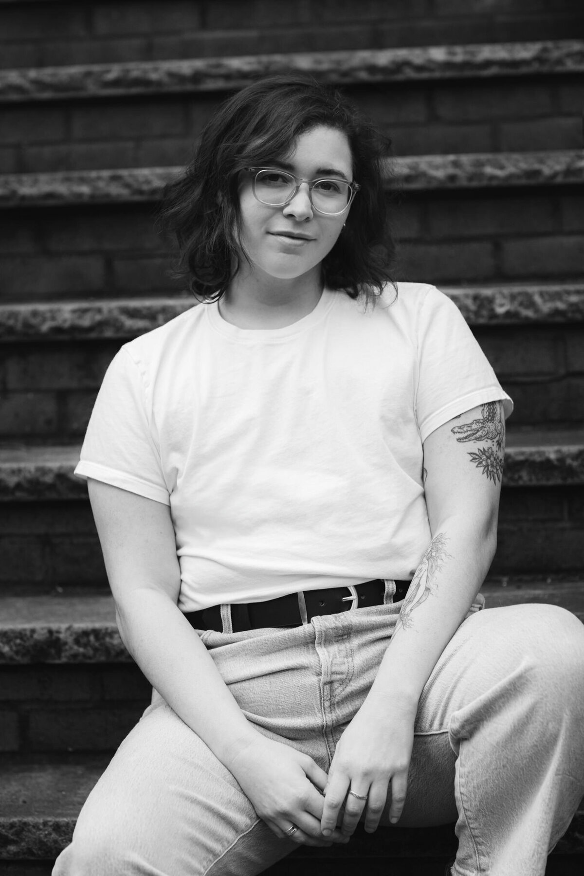black and white portrait of author casey mcquiston sitting on a stoop in lic