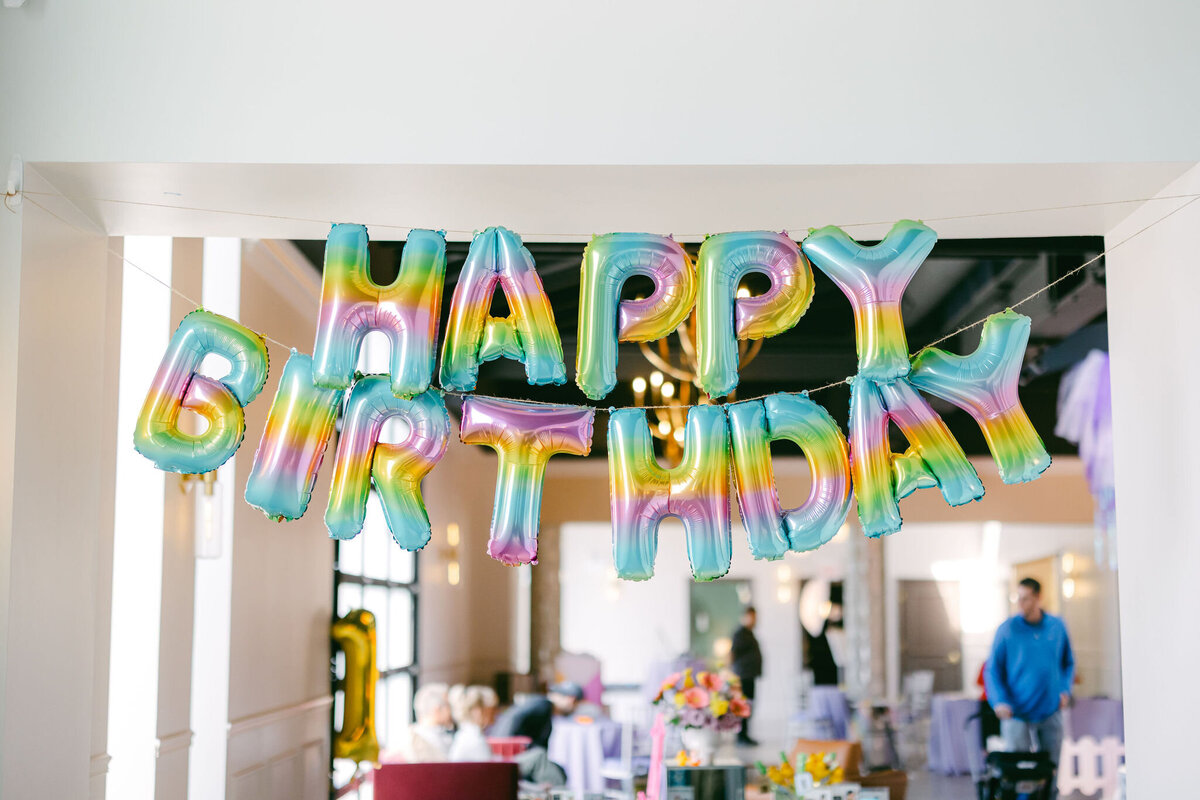Colorful bounce house at a children’s birthday party venue, surrounded by vibrant balloons, playful decorations, and festive table settings, creating a fun and lively atmosphere