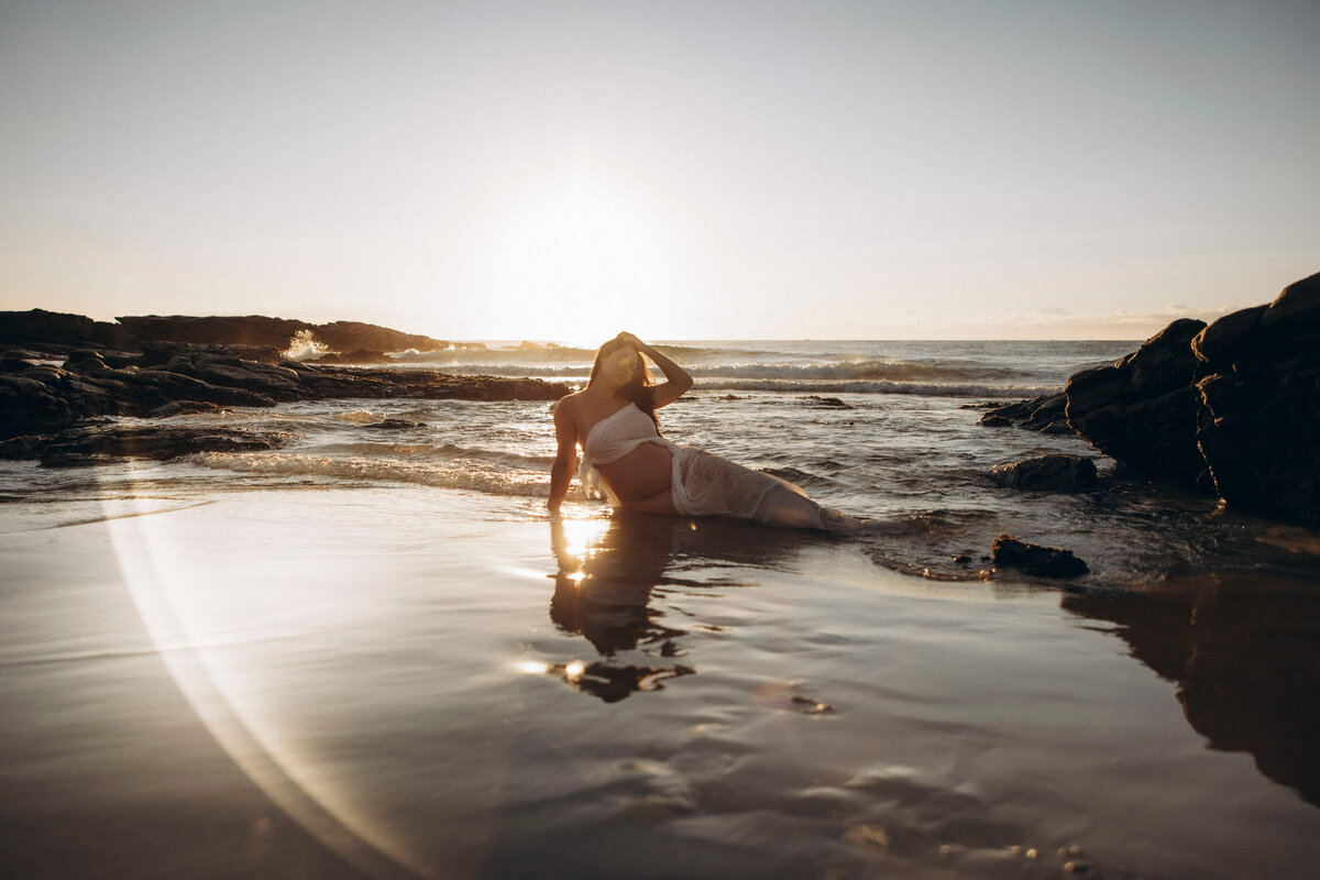 pregnant woman lying in the sea on a beach