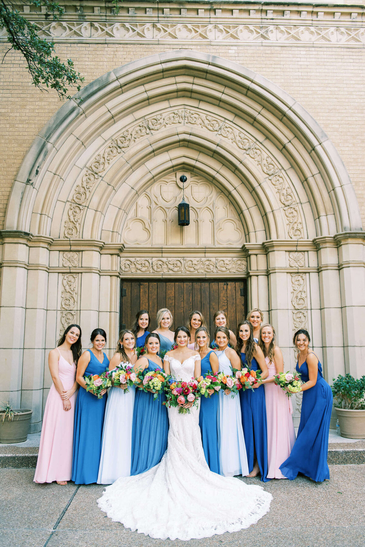 Bridal party and bride pose in front of ornate cathedral building in Fort Worth