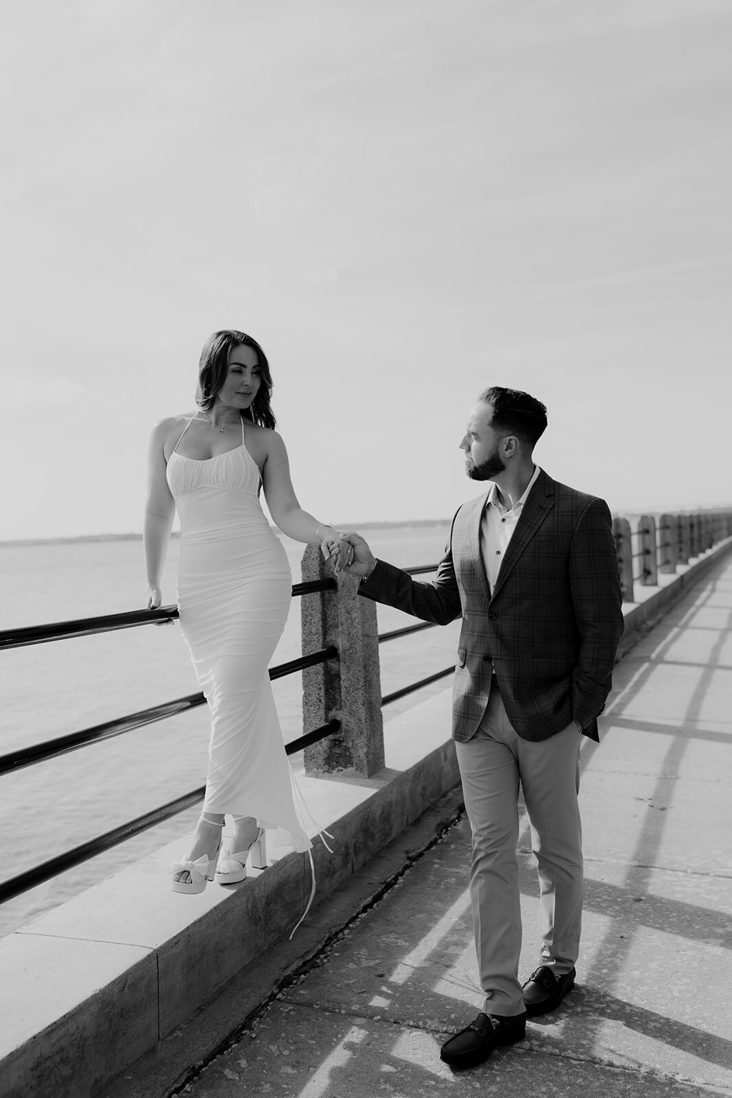 Charleston Engagement Photo locations inviting couple to walk on wall with harbor in background