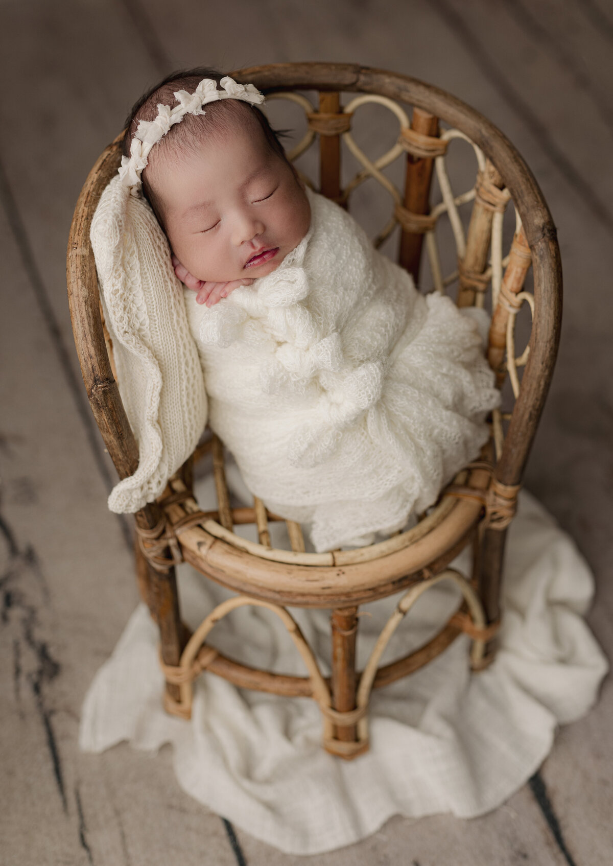 baby wrapped in white laying on chair