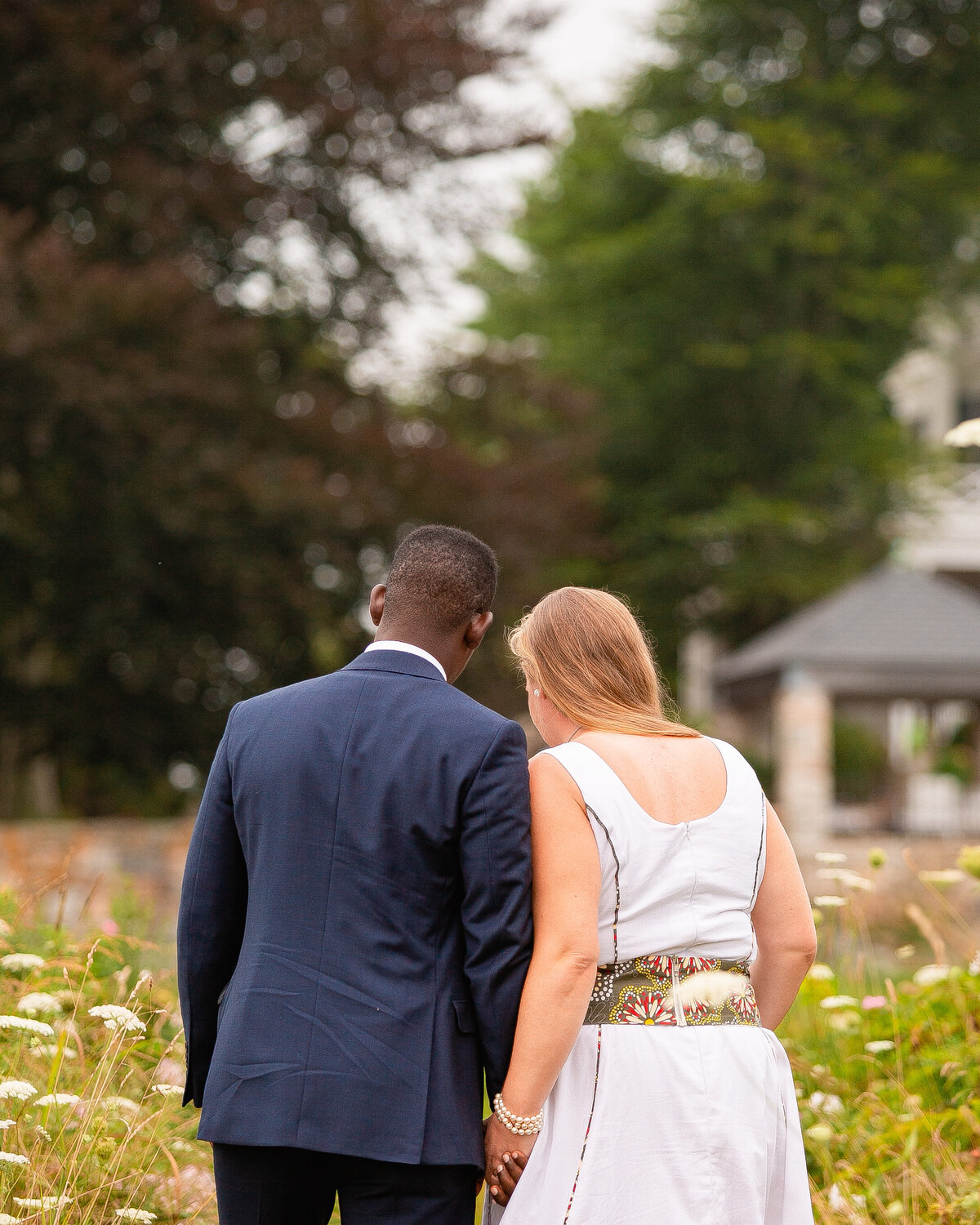 Newlyweds walk through a field of flowers in Stonington, CT.
