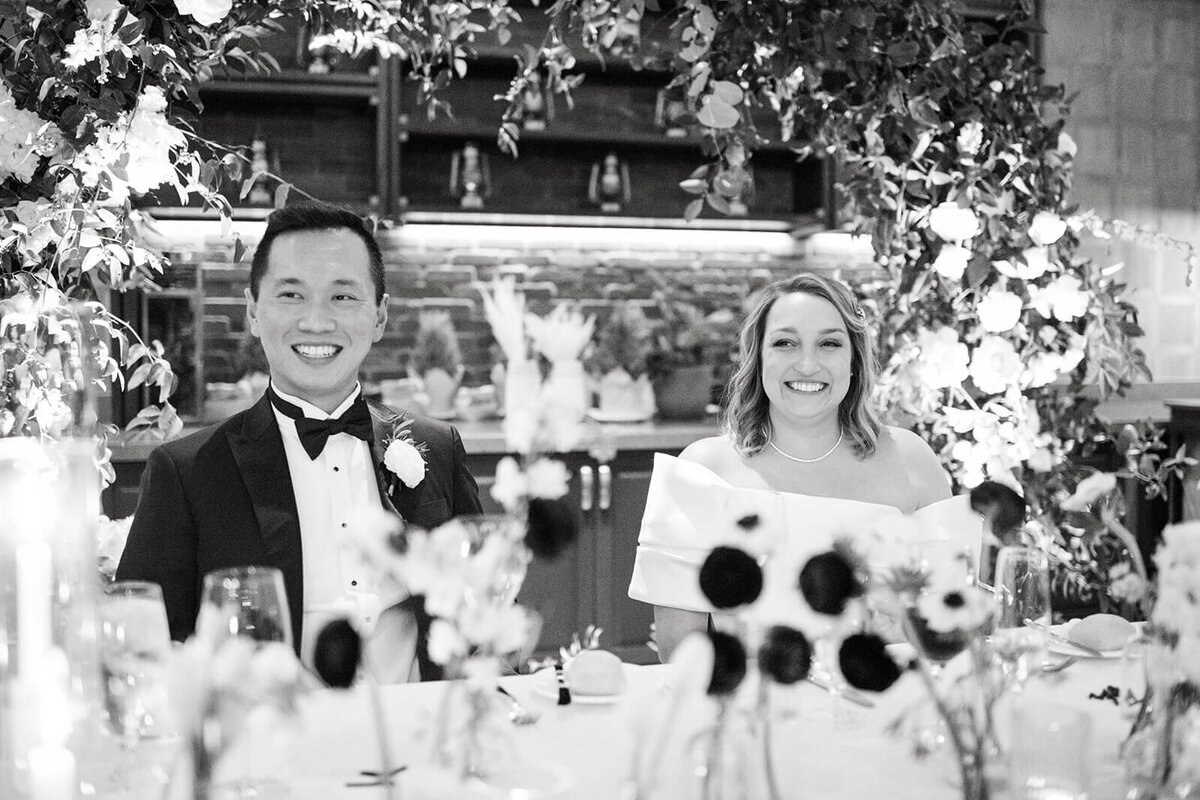Bride and groom at their sweetheart table at St. Regis Aspen, sharing a moment surrounded by floral arrangements and candlelight.