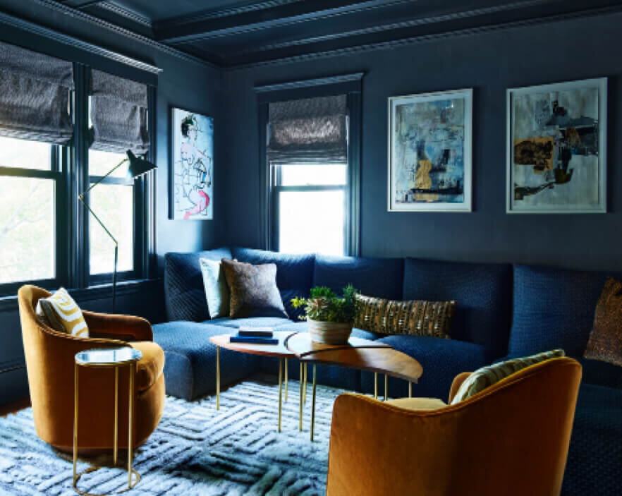 Best Boston interior design firms created a navy blue family room with modern furniture and vintage pieces, blending classic style with contemporary design.