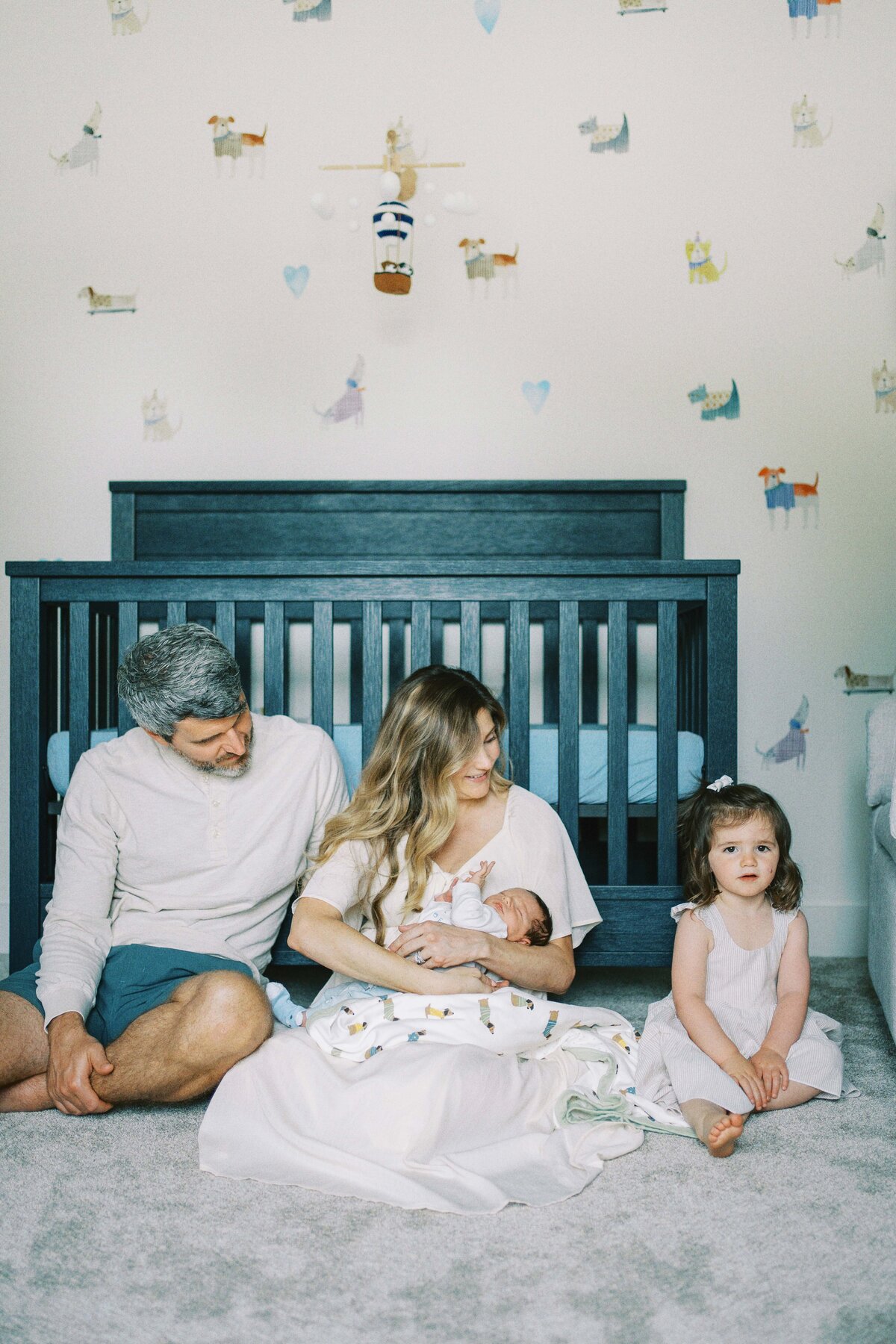 mom and dad smiling at big sister during baby's newborn photos